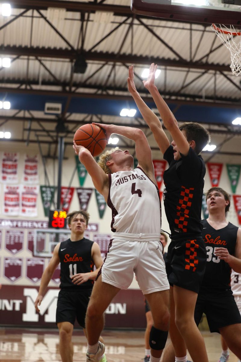 Senior Cole Thurn (4) stretches to get a good shot as he's being blocked by a Solon player Dec. 17.