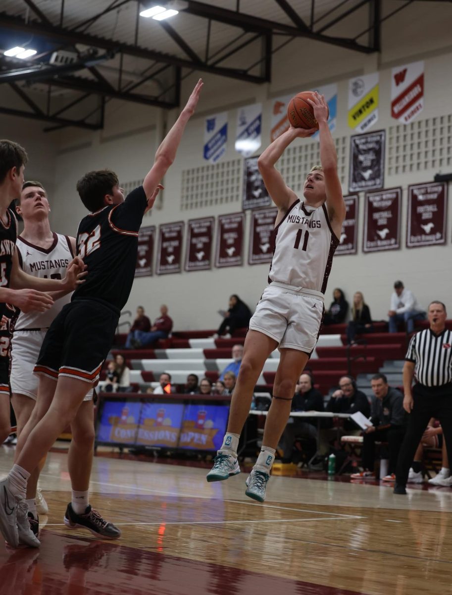 Junior Kellen Haverback (11) Jumps away from his Hawk opponent to shoot the basketball Jan. 28.