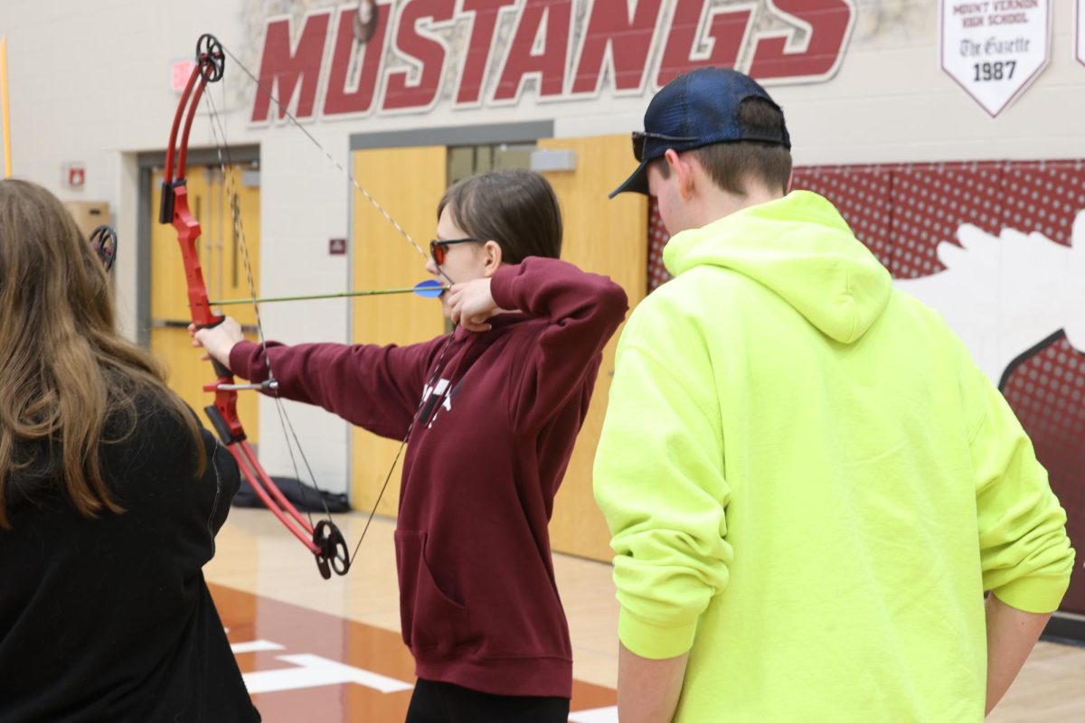 Payson Burge helps his little sister Jaydan Burge with archery durning the Freshmen Experience J-term.