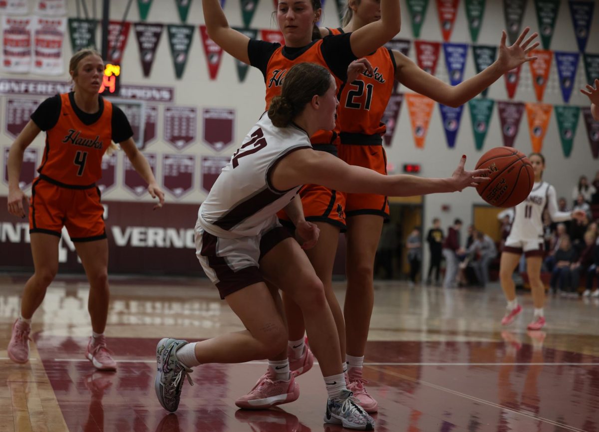 Junior Courtney Franck (22) reaches across her opponent to pass the basketball to her teammate. The Mustangs ended up winning the game against the Hawks 67-40 on Jan. 28.