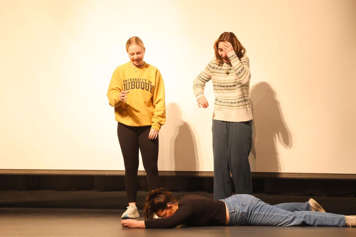 Junior Cait O'Connor falls to the floor trying to pick up a cupcake from Senior Natalie Thuerauf during their improv sketch  Feb.15. 