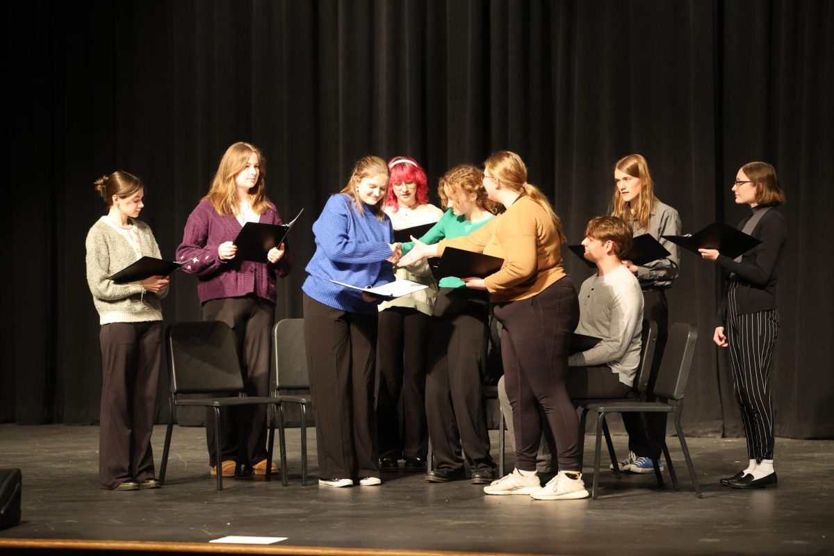 Senior Charlotte Hand shakes hands with juniors Eva Bishop and Ellah Shook during their readers theatre  "Then I'll be happy" Feb.15.