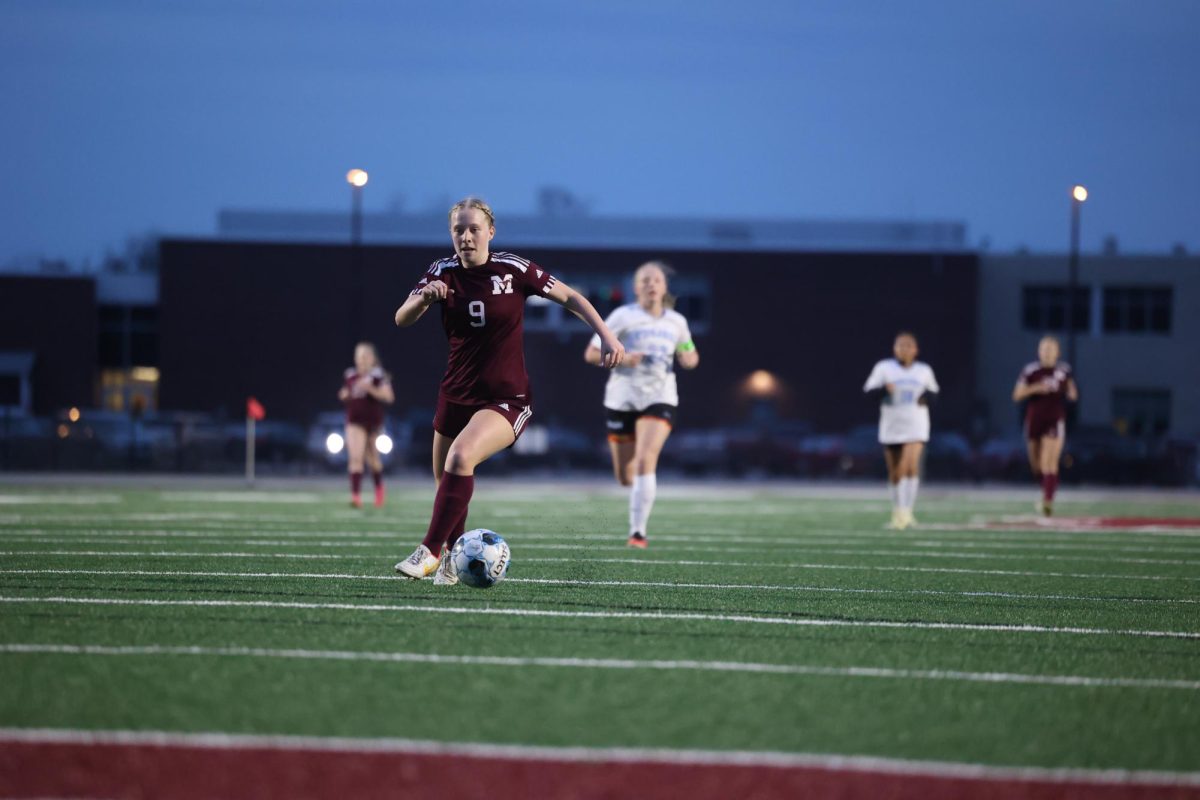 Senior Natalie Thuerauf (9) carries the ball down the field as she winds up to score a goal April 17. 