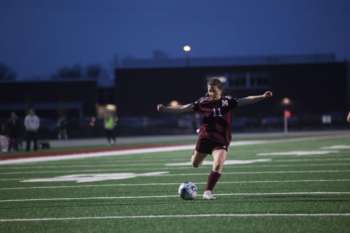 Junior Emara Perrault (11) winds up to shoot the soccer ball into the net, successfully completing a goal April 17.
