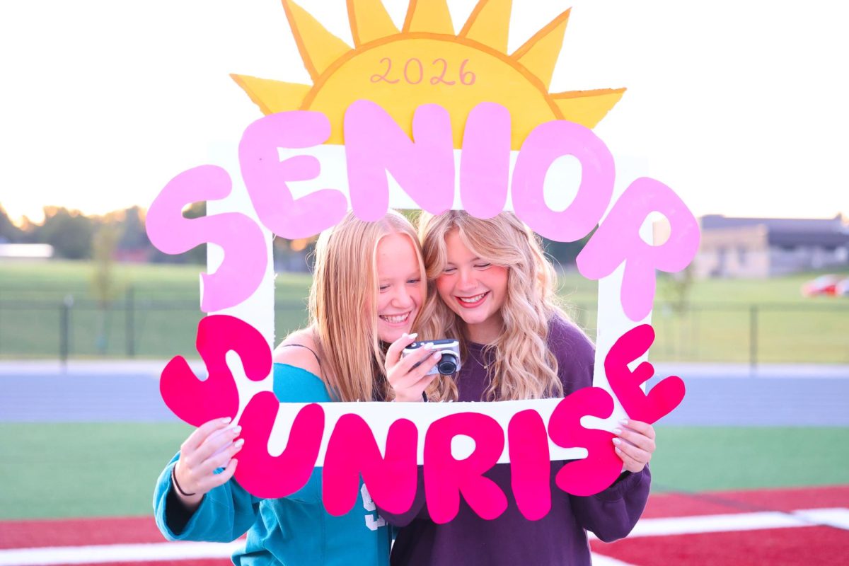 Seniors Emma Hoffman and Norah Weber look at their selfie capturing their experience celebrating the last first morning of the school year Aug. 25.