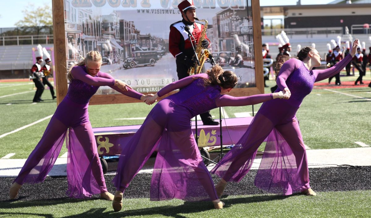 Sophomores Adrienne Ruhland, Marlena Rodenberg, and senior Malena Koehn dance together during the Marching Mustangs show on Sept. 27.
