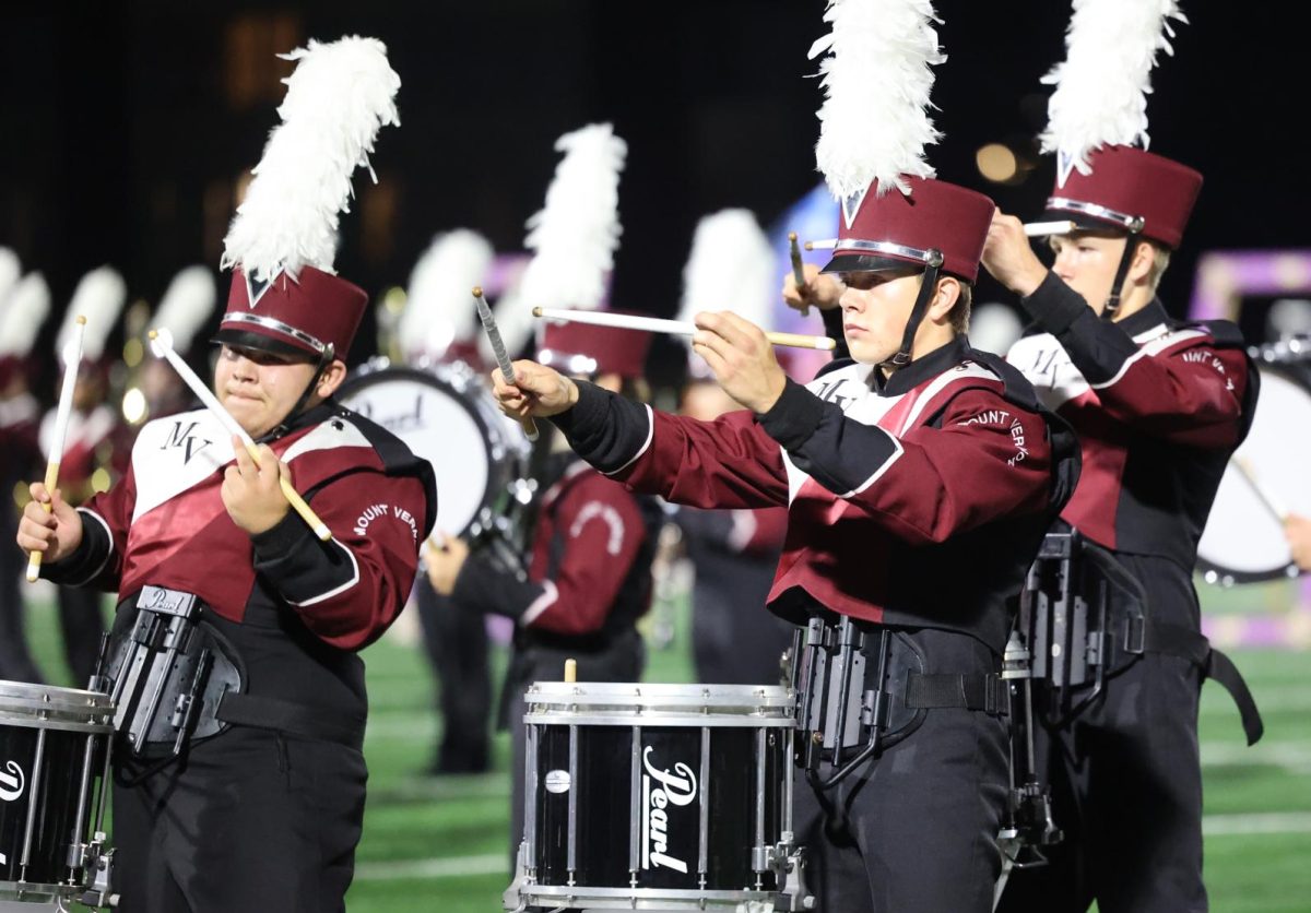 Senior Lewis Krob leads the drumline during their football halftime show. 