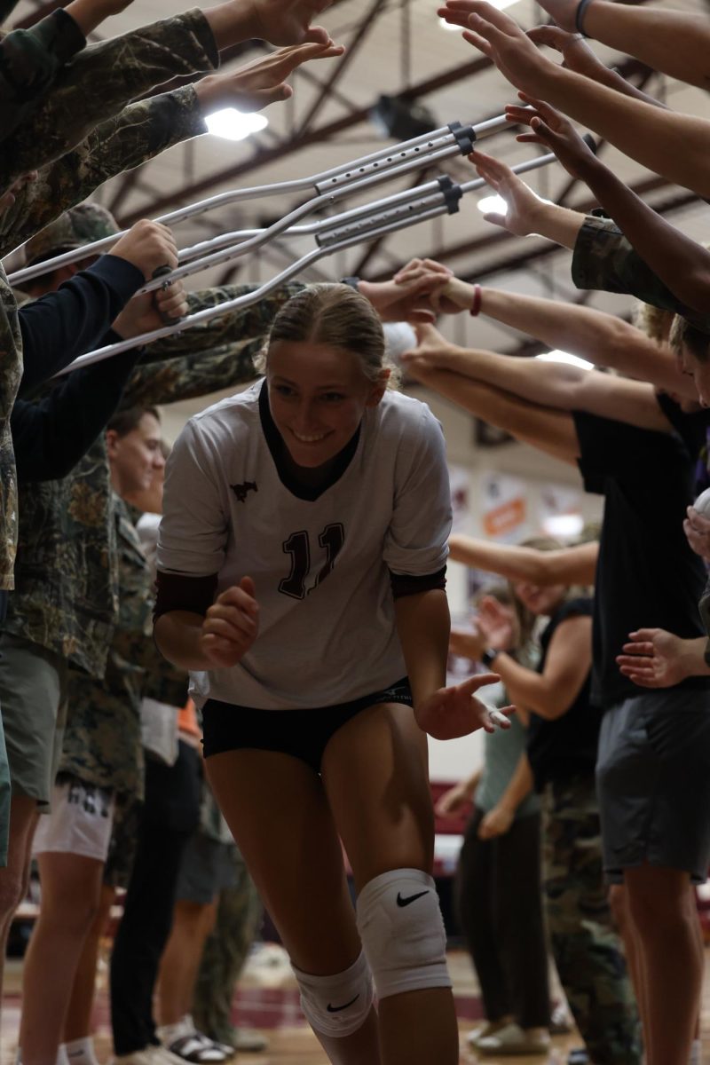 Sophomore Ella Wilson runs through the tunnel created by students after the Mustang win on Tuesday night. 