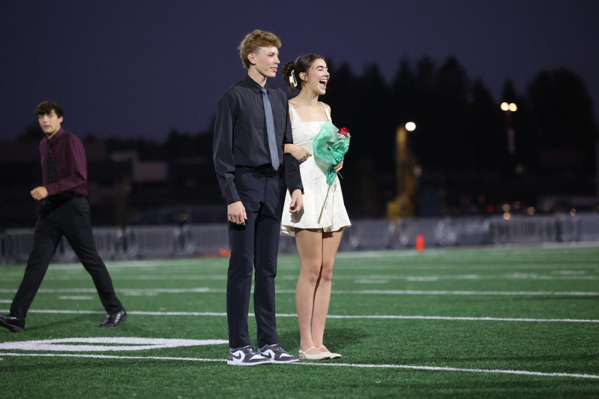 Seniors Grace Hale and Landon Wilson join together on the middle of the field to hear the crowd roar in celebration of their crowning on Oct. 2. 