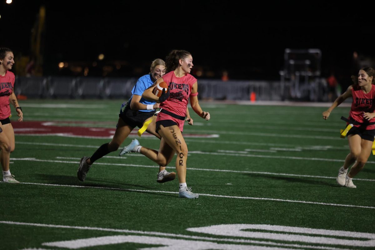 Senior Kaia Swaim runs with the ball as junior Lucy Wischmeyer runs to get her flag Oct. 2. 
