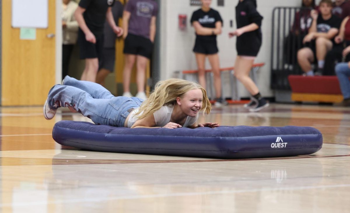 Senior Emma Hoffman dives on to an air mattress during the pep rally relay race against the Mount Vernon band and tennis teams. 