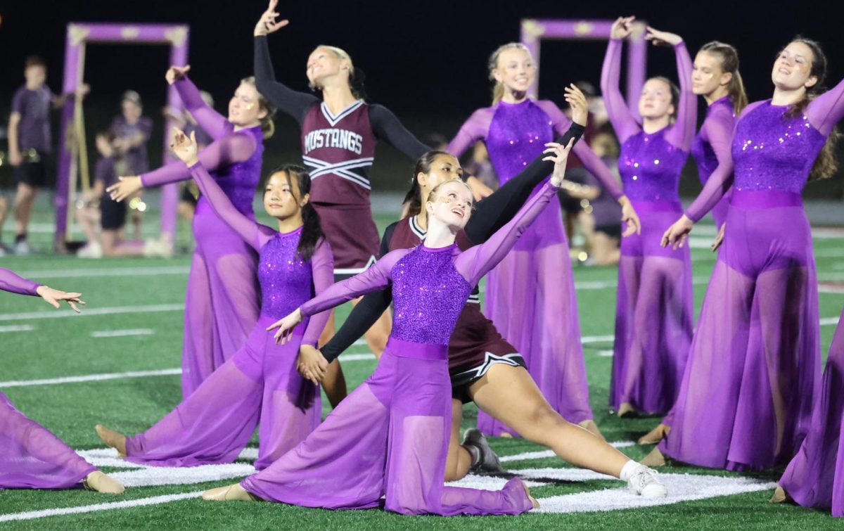 Senior color guard captain Ingrid Morf poses with the rest of the guard as they begin the homecoming halftime show. 