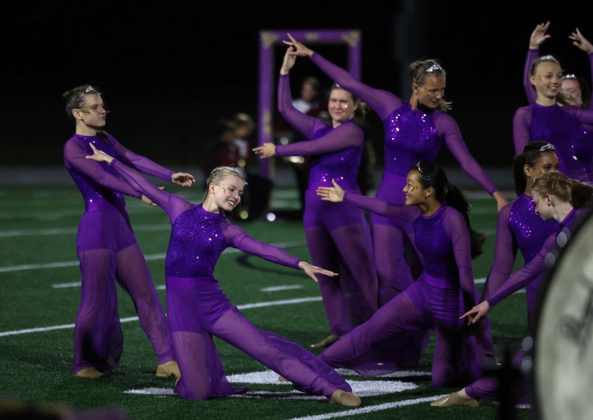 Sophomore Hannah Morf and the rest of the color guard pose together as the marching band show begins.