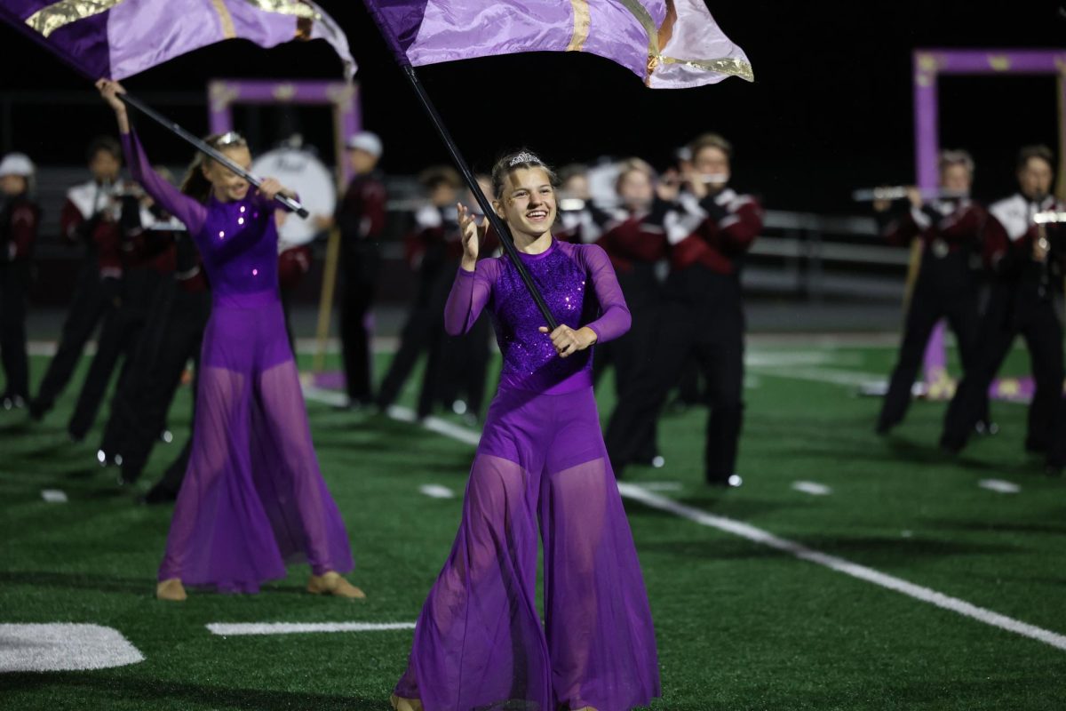Sophomore Kate Martin waves her flag with the color guard at the beginning of their show on Oct. 20.