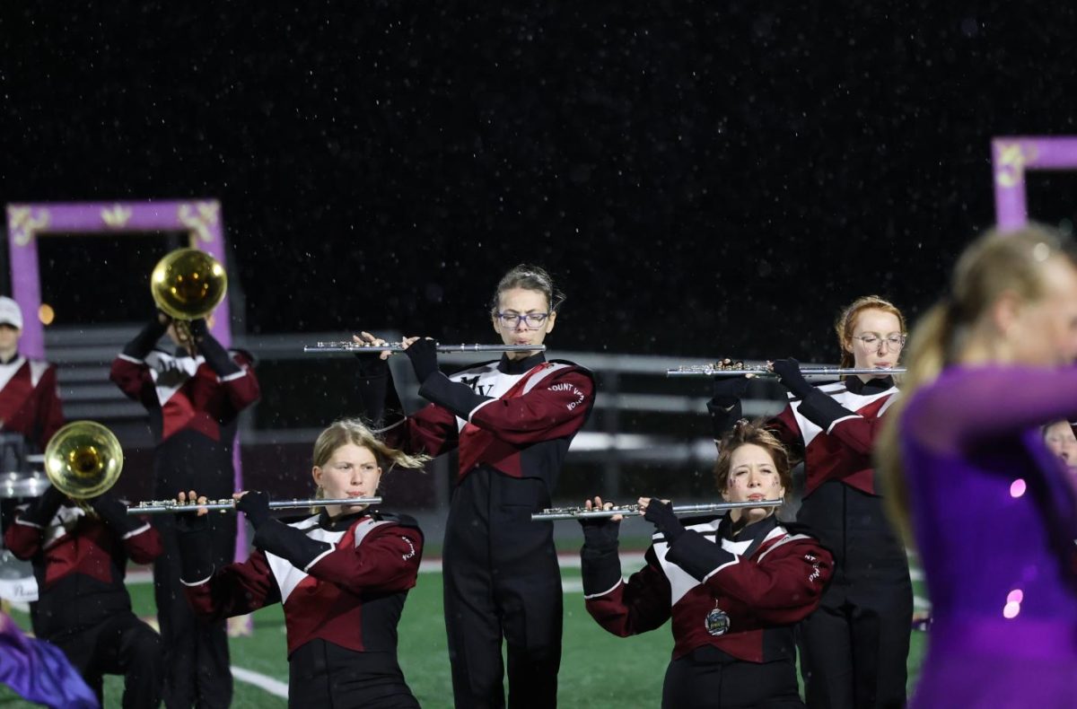 The Marching Mustangs flutes play through the rain together on Oct. 20.