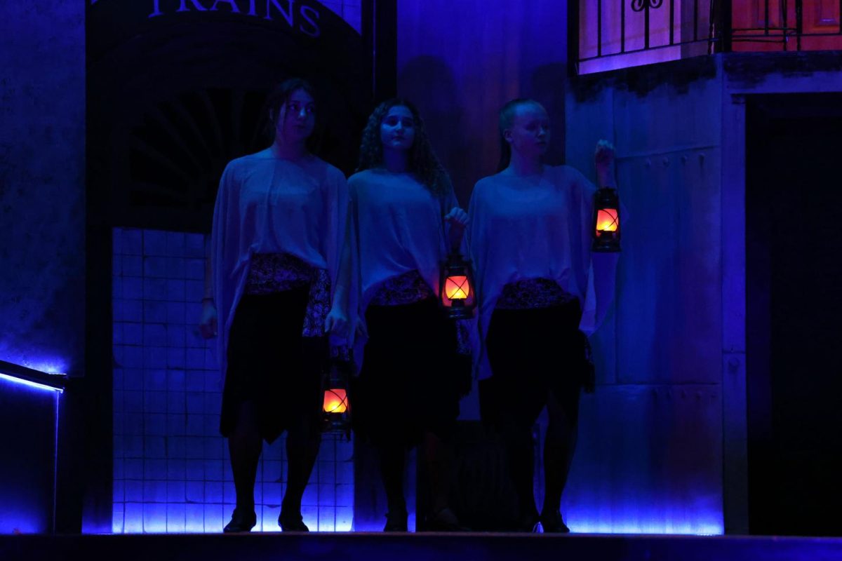 Seniors Addi Whisner, Grace Bausch, and Emma Hoffman (The Fates) watch as Orpheus and Eurydice begin their journey.