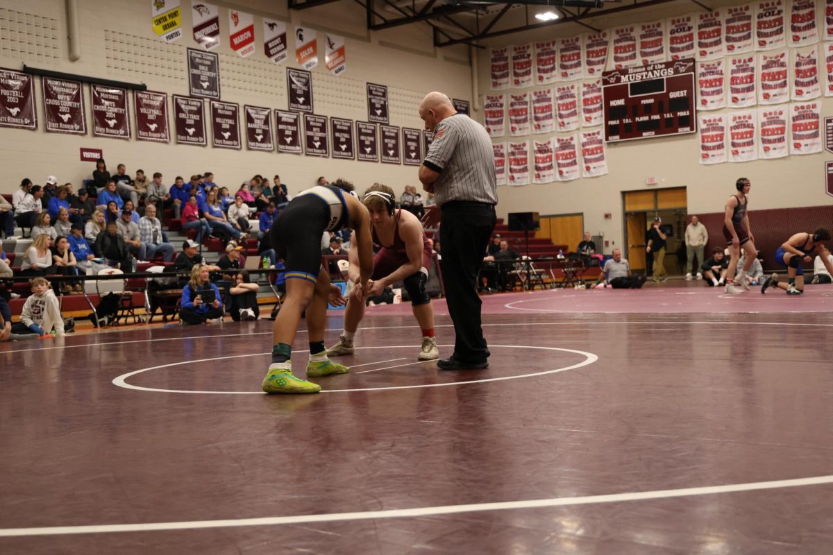 Senior Caysen Curran shakes the hand of the Benton student he is about to wrestle.