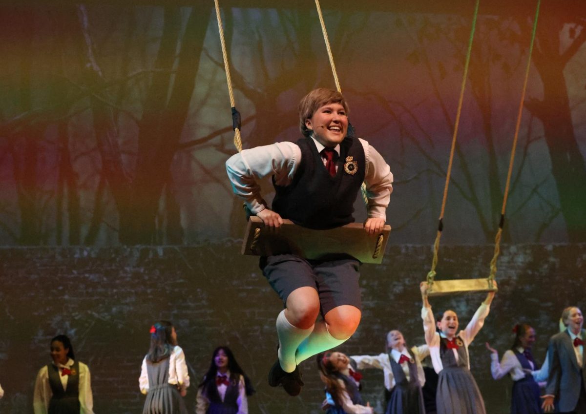 Senior Mae Krapfl swings above the stage during the song "When I Grow Up". 