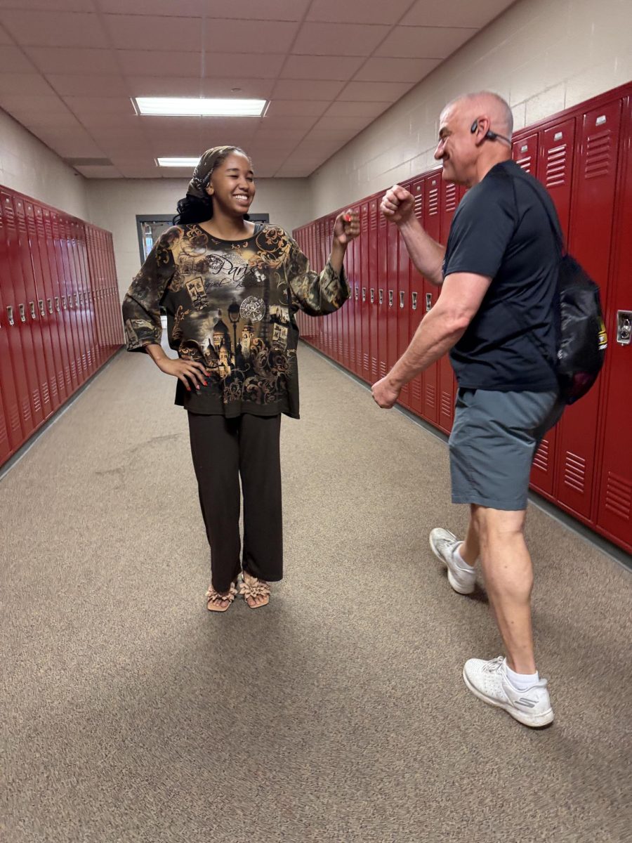 Social Studies teacher Ed Timm gives senior Rose Daoud a fist bump in the hallway April 17.