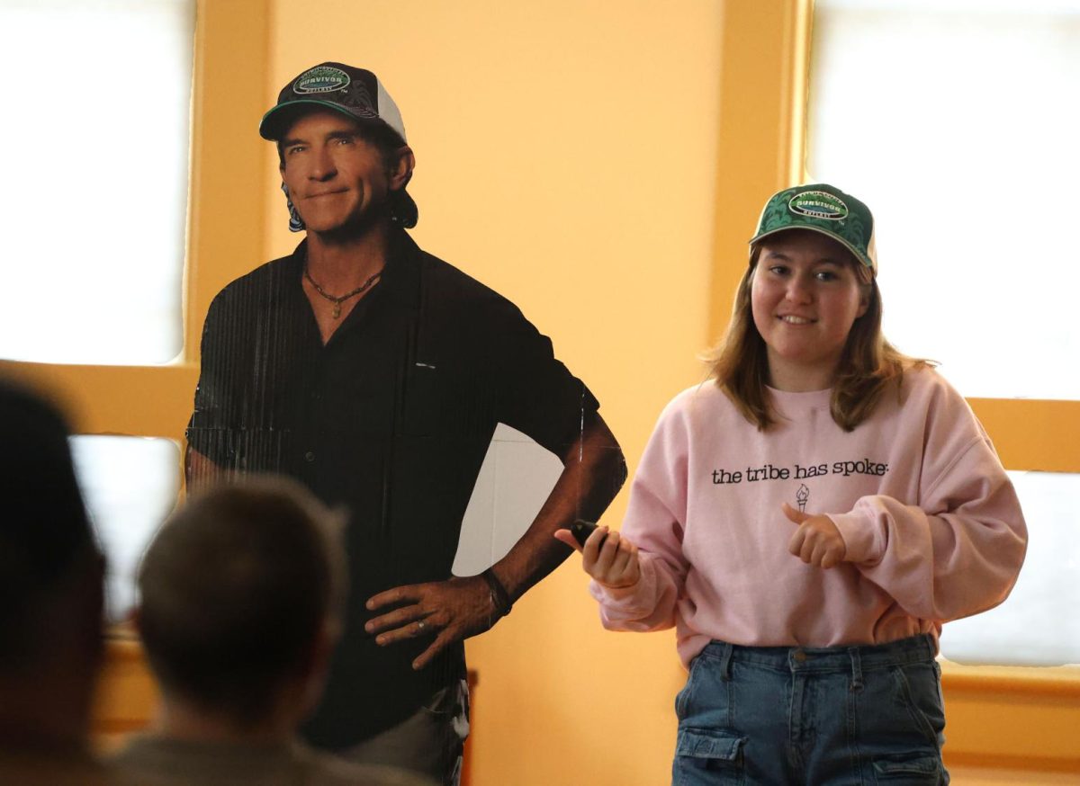 Senior Mae Krapfl introduces her Jeff Probst cardboard cutout during her "How to Win Survivor" Expository Address on March 29.