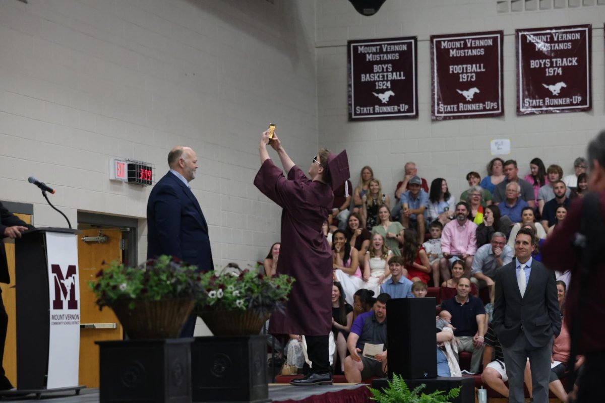 Kevin Zehms takes a selfie on stage before receiving his diploma May 23.